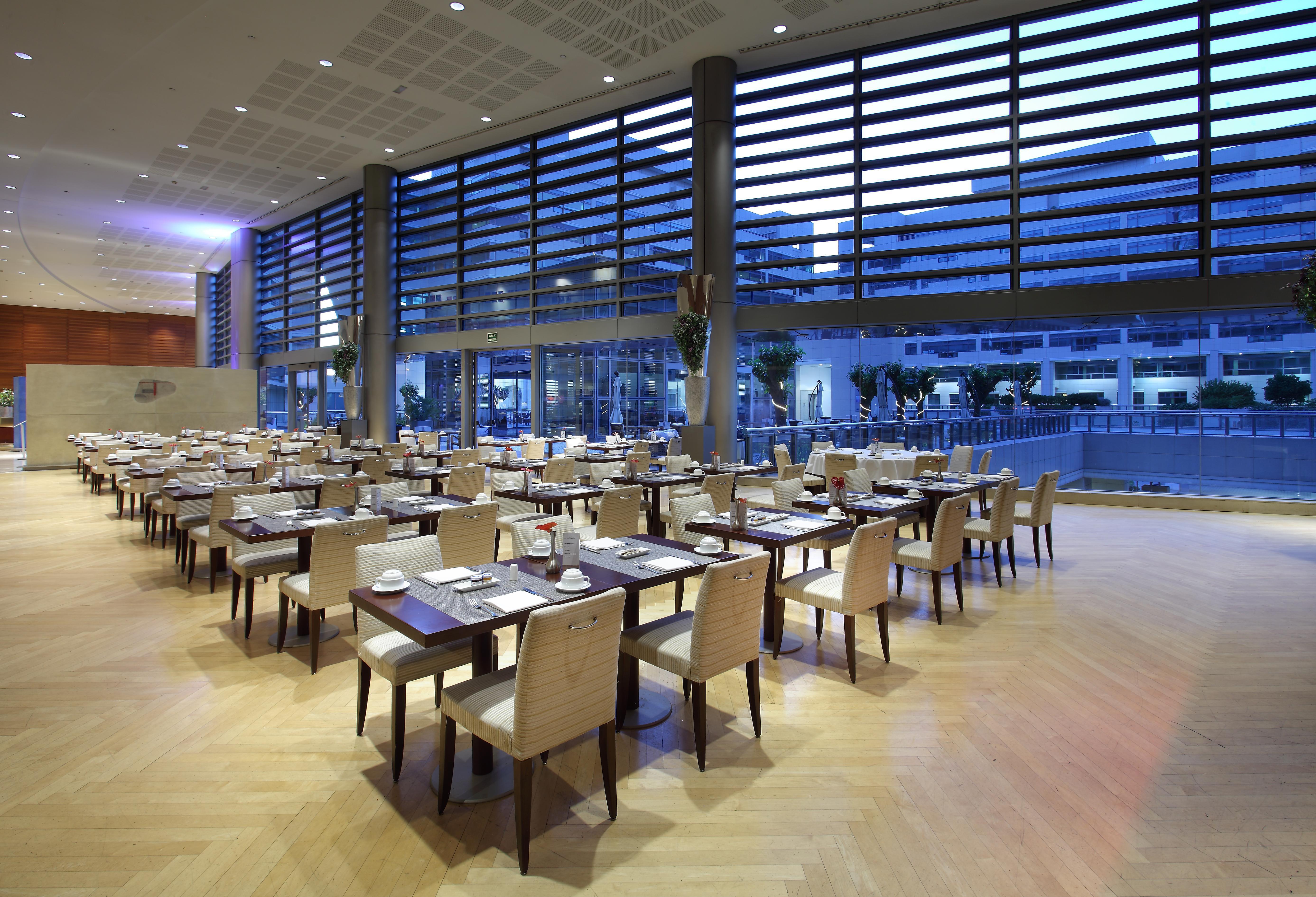 Eurostars Grand Marina Hotel Gl Barcelona Ngoại thất bức ảnh The photo depicts a modern restaurant interior. It features a spacious dining area with several tables arranged neatly throughout. Each table is set with plates and utensils, suggesting readiness for guests. Large windows allow natural light to fill 