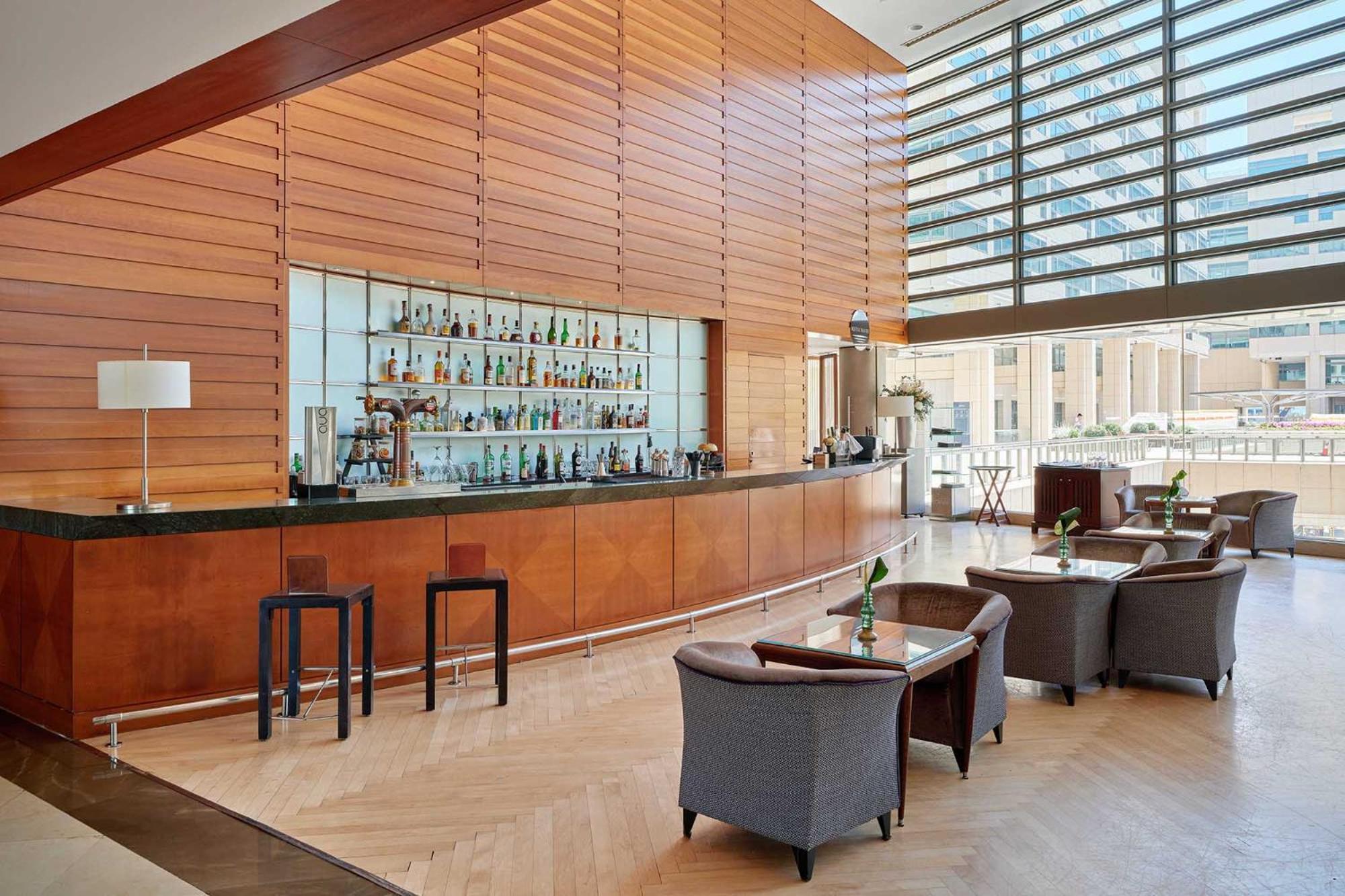 Eurostars Grand Marina Hotel Gl Barcelona Ngoại thất bức ảnh The photo shows a modern bar area with a sleek, minimalist design. There is a long, polished bar countertop behind which various bottles of drinks are displayed. The walls feature wooden paneling that creates a warm ambiance, and large windows allow 