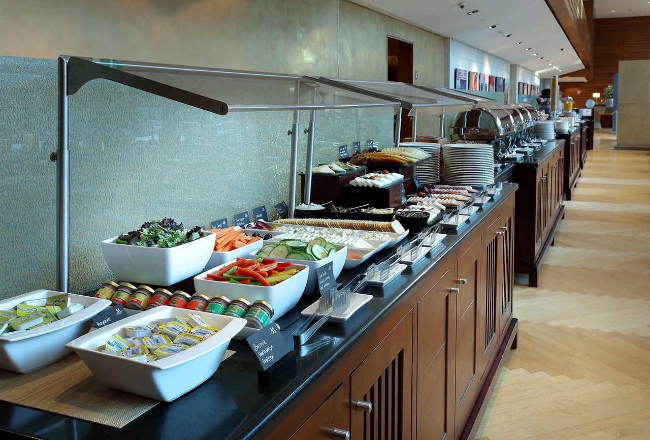 Eurostars Grand Marina Hotel Gl Barcelona Ngoại thất bức ảnh The photo shows a buffet spread featuring a variety of dishes arranged along a long serving counter. There are several bowls and platters containing fresh salads, sliced vegetables, and other food items. The setting appears modern and well-organized,