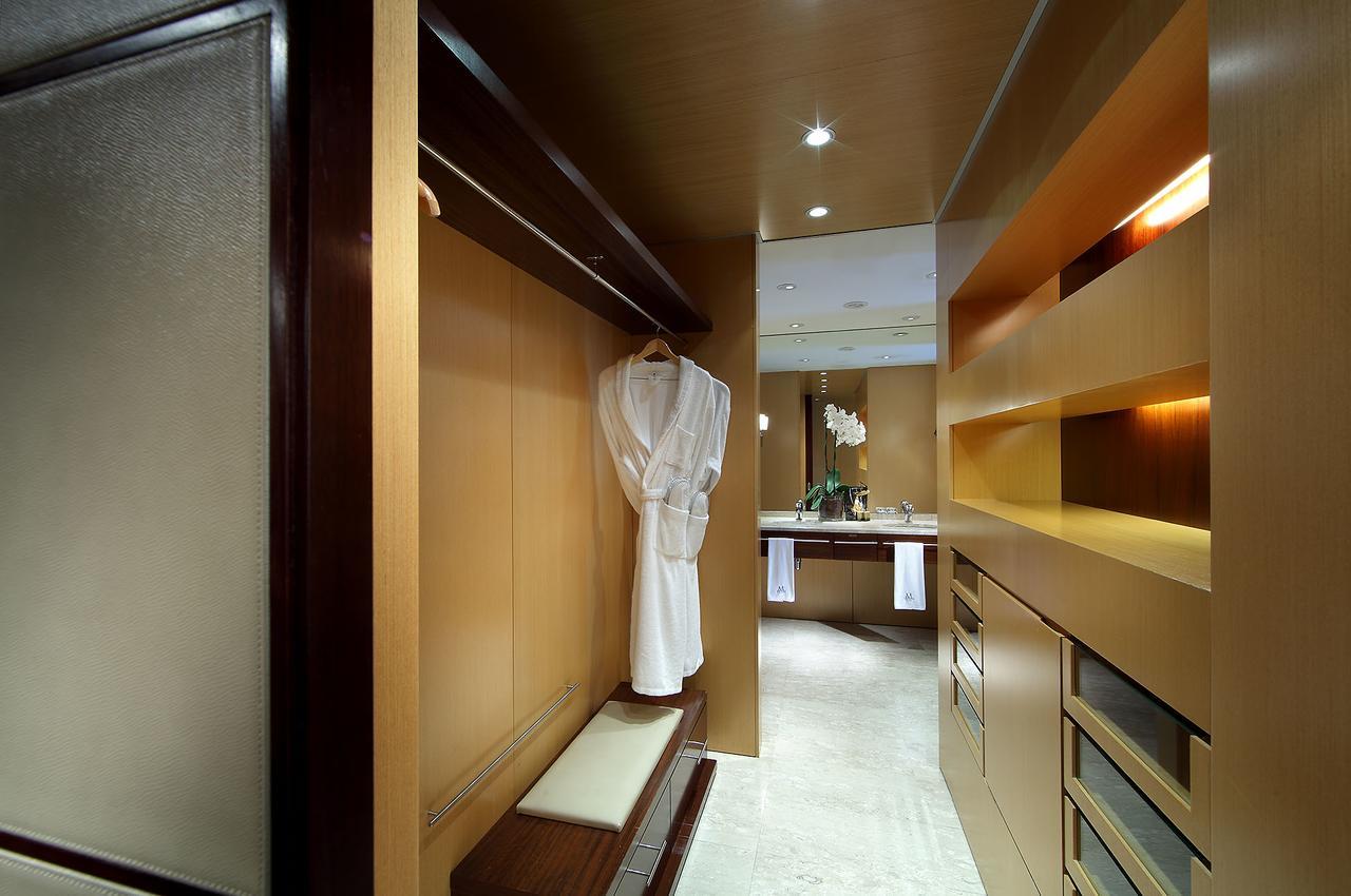 Eurostars Grand Marina Hotel Gl Barcelona Ngoại thất bức ảnh The photo depicts a stylish interior space, likely a dressing area or walk-in closet. The walls are finished in warm wood tones, creating a modern and elegant atmosphere. A white robe hangs on a sleek hook, and there is a bench next to it. The area i